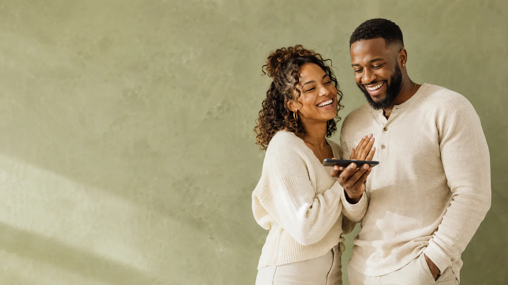 A couple laughing while listening to a personalized song from a phone speaker